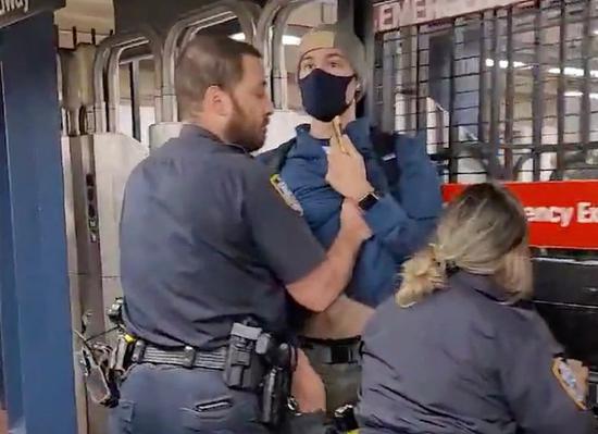 Screenshot of a video clip that shows two New York City police officers ejecting a masked subway rider who asks them to put on masks
