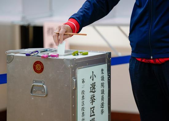 A voter casts a ballot at a polling station for Japan's general election in Tokyo, Japan on Oct. 31, 2021. (Photo by Christopher Jue/Xinhua)