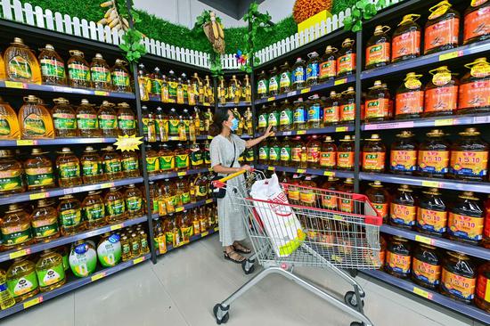 A customer buys edible oil at a supermarket in Qingzhou, East China's Shandong province, Aug 9, 2021. (Photo/Xinhua)