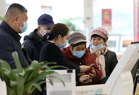 A bank employee (center) addresses customers' queries on pension account in Yangzhou, Jiangsu province, in January. (Photo: China Daily/Zhao Hongwei)