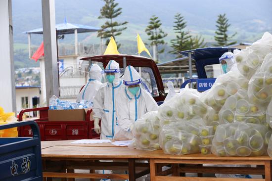 Workers receive food prepared for people under quarantine for medical observation at the entrance of a centralized isolation site in Wanding town of Ruili city, Yunnan province, on Nov 13, 2021. (Photo: chinadaily.com.cn/Wu Xiaohui)