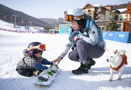 Yuji takes off her snowboard with the help of her mom. (Xinhua/Zhang Fan)