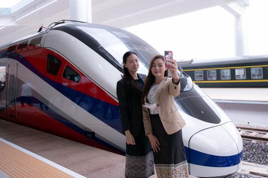 Two women pose for photos with the Lane Xang EMU train at the China-Laos railway Vientiane station in the Lao capital Vientiane, Oct 16, 2021. (Photo/Xinhua)