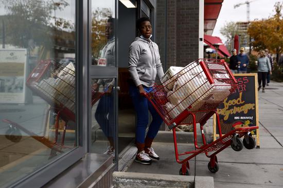 A customer walks out of a supermarket with a loaded pushcart in Washington, on Nov 12, 2021. (Photo/Xinhua)
