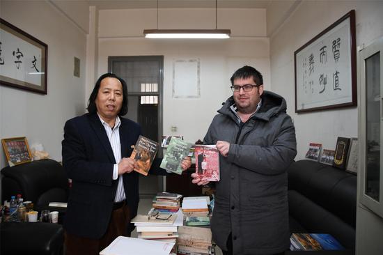 Robin Gilbank (R) and Hu Zongfeng (L) with three Chinese novels that are translated by them and published, Jan. 27, 2018. (Photo/Xinhua)