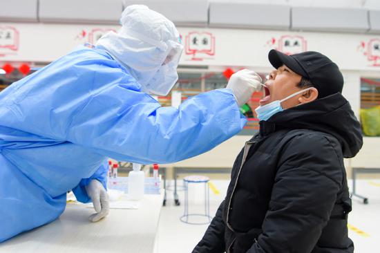 A staff member takes a swab sample from a resident for nucleic acid test at a testing site in Manzhouli, North China's Inner Mongolia autonomous region, Nov 29, 2021. (Photo/Xinhua)
