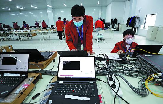Workers test devices at the main logistics center for the Beijing 2022 Winter Olympic Games in Beijing on Thursday. (Photo by Zhang Wei/China Daily)