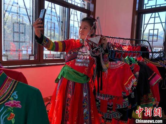 Tu Guojia shows She people's clothes. (Photo/China News Service)