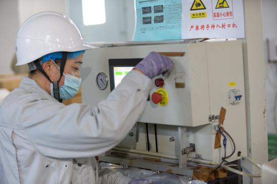 An employee operates a machine at the production workshop of a polysilicon company in northwest China's Xinjiang Uygur Autonomous Region, Dec. 16, 2021. (Xinhua/Gao Han)