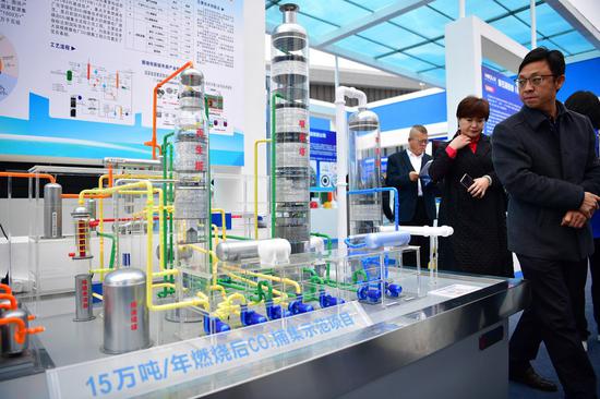 Visitors watch the model of a demonstration project for carbon dioxide capture, in an energy and chemical industry expo held in Yulin, northwest China's Shaanxi Province, Oct. 13, 2021. (Xinhua/Shao Rui)