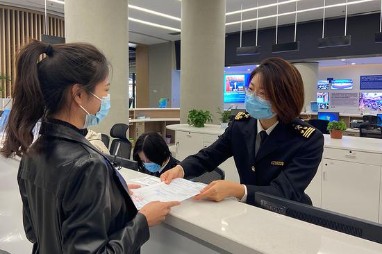 A customs officer at the RCEP Qingdao Enterprise Service Center helps a woman apply for certificates of origin. (Photo by Zhang Fang/for China Daily)