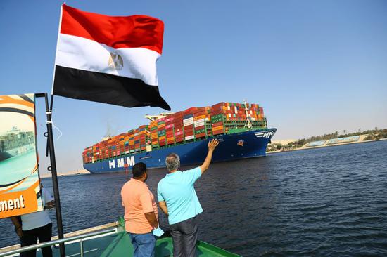 People watch a ship sailing on the Suez Canal in Ismailia Province, Egypt, on Oct. 5, 2021. (Xinhua/Ahmed Gomaa)