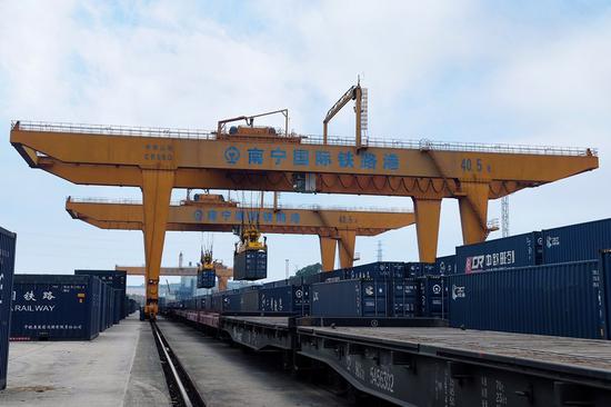 A gantry crane loads containers onto a freight train in Nanning international railway port in south China's Guangxi Zhuang Autonomous Region, Dec. 31, 2021. (Xinhua)