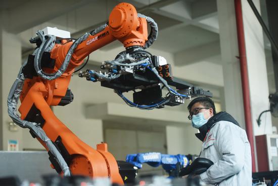 An engineer fine-tunes an industrial robot in Hangzhou, Zhejiang province, on Jan 16, 2022. (Photo by Long Wei/For China Daily)