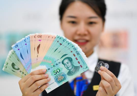 A woman shows banknotes and coins included in the 2019 edition of the fifth series of the renminbi. (Photo/Xinhua)