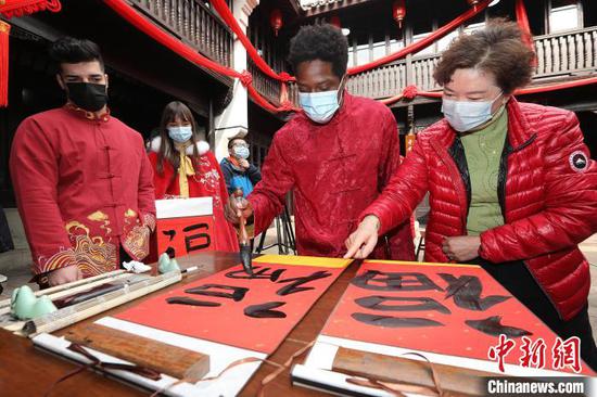 A foreign young man writes Chinese character "Fu" guided by a teacher. (Photo/China News Service)