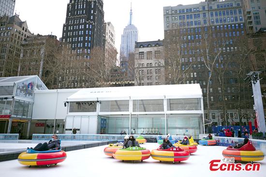 People enjoy a bumper car ride on ice at Bryant Park in New York, United States, Jan. 20, 2022. The "Bumper Cars on Ice" program was back on Jan. 14 this year. (Photo: China News Service/Wang Fan)