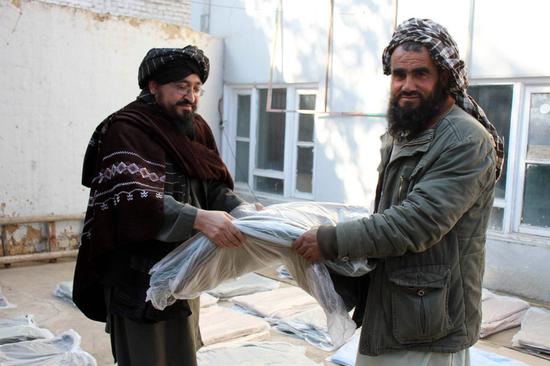 People receive relief assistance donated by China in Maimana, capital of Faryab province, Afghanistan, Jan. 10, 2022. (Photo by Qamaruddin Poya/Xinhua)


