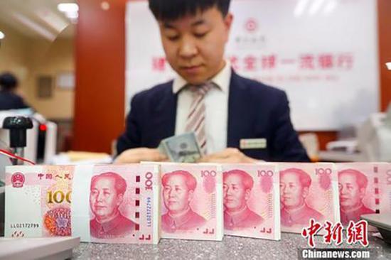 A bank staff member counts money. (Photo/China News Service)