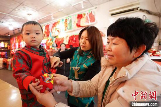 A small child tries new clothes in a clothing store in Shengfang Ancient Town, Bazhou, Hebei. (Photo/China News Service)