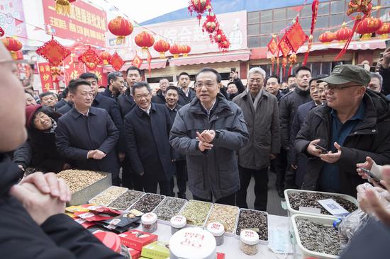 Chinese Premier Li Keqiang visits a market stall to learn about the supply, sales and prices of holiday goods in the Jinsanjiao market, Jinchang City of northwest China's Gansu Province, Jan. 27, 2022. (Xinhua/Wang Ye)