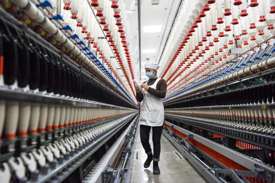 A staff member works at a spinning factory in Moyu county, Northwest China's Xinjiang Uygur autonomous region, Jan 11, 2022. (Photo/Xinhua)