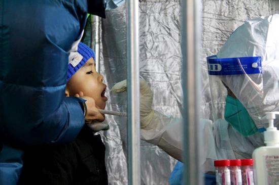 A medical worker takes a swab sample from a boy for nucleic acid test at a COVID-19 testing site in Fengtai District in Beijing, capital of China, Jan. 23, 2022. (Xinhua/Tang Rufeng)