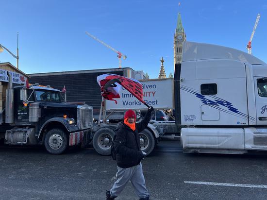 A protester waves a flag in front of trucks in Ottawa, Canada, on Jan. 28, 2022. (Xinhua/Lin Wei)