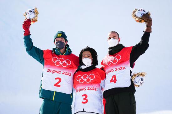 Hirano Ayumu (C) of Japan, Scotty James (L) of Australia and Jan Scherrer of Switzerland pose for photos during the flower ceremony after the men's snowboard halfpipe final at Genting Snow Park in Zhangjiakou, north China's Hebei Province, Feb. 11, 2022. (Xinhua/Xu Chang)