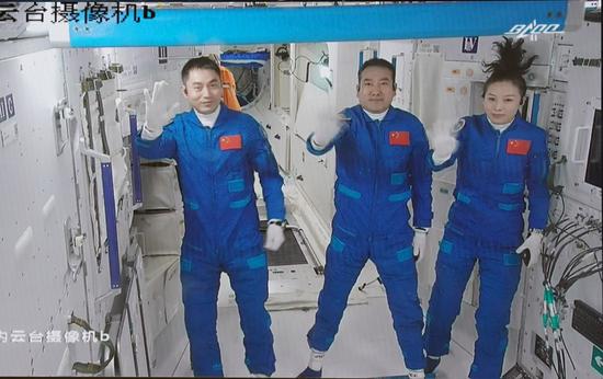 Screen image captured at Beijing Aerospace Control Center in Beijing, capital of China, Oct. 16, 2021 shows three Chinese astronauts, Zhai Zhigang (C), Wang Yaping (R) and Ye Guangfu, waving after entering the space station core module Tianhe. (Xinhua/Tian Dingyu)