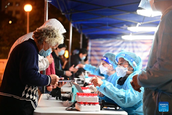 A medical worker registers personal information of a woman at a COVID-19 testing site in Hong Kong, Jan 24, 2022. (Photo/Xinhua)