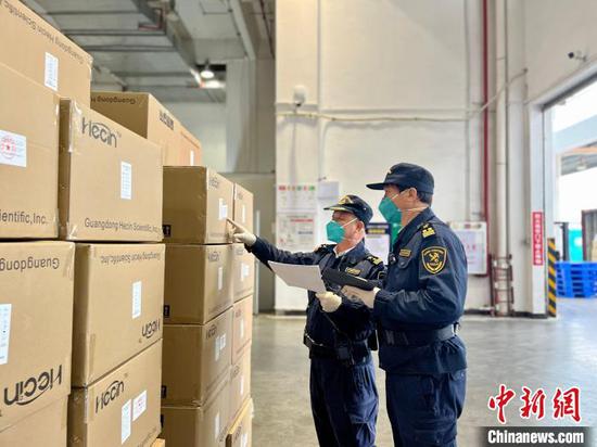 Two staff members of Shatian Customs inspect COVID-19 supplies. (Photo/China News Service)