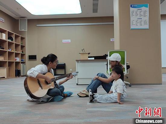 A medical worker plays music for a child patient in Xi'an, Shaanxi Province. (Photo/China News Service)