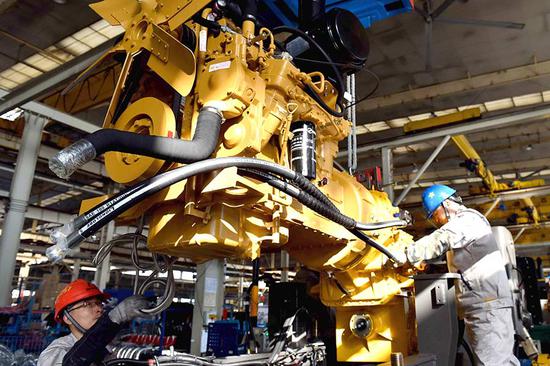 Employees of an engineering machinery manufacturer in Shandong province work on the company's production line of loaders. (Photo/Xinhua)