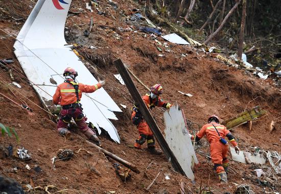 A recovery team searches through the debris at the China Eastern Airlines Flight MU5735 crash site on Thursday in Tengxian county, Guangxi Zhuang autonomous region. Various items from the cockpit have been found, including crew manuals and ID cards. (LU BOAN/XINHUA)