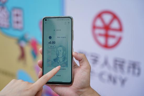 A staff member of the Bank of Communications Beijing Branch instructs a visitor to open a digital RMB wallet on a mobile phone, on June 16, 2021. (Photo/Xinhua)