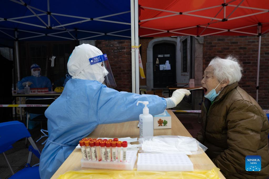 A medical worker takes a swab sample from a woman for nucleic acid test in Changning District of east China's Shanghai, April 1, 2022. Shanghai has launched a nucleic acid testing campaign in areas west of the Huangpu River from Friday amid the second phase of the city's closed-off management. (Xinhua/Jin Liwang) 