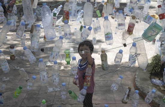  A boy views an installation made of plastic bottles during the Marine Debris Festival, held by the local community as a campaign to save the beach from plastics pollution, in Poliwali Mandar district, West Sulawesi, Indonesia, Oct. 3, 2021. (Photo by Yusuf Wahil/Xinhua)