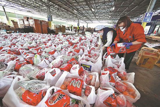 Staff members pack daily necessities from group purchases at a Metro store in Shanghai on April 13, 2022. （Photo by Zhu Xingxin/China Daily）
