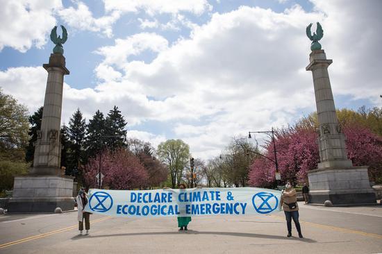 Activists hold a sign on Earth Day in front of Prospect Park in the Brooklyn borough of New York, the United States, on April 22, 2021. (Photo by Michael Nagle/Xinhua)
