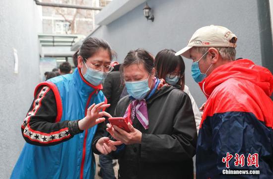 A volunteer helps an old woman to make an appoinment of COVID-19 vaccination in Beijing, March 18, 2021. (Photo/China News Service)