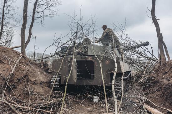 A Ukrainian soldier covers an armored vehicle with branches in Donbass on April 12, 2022. (Photo by Diego Herrera/Xinhua)