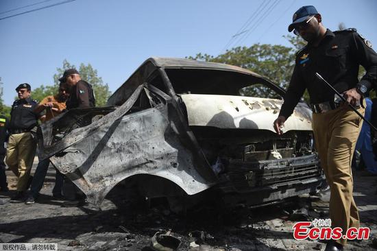 Pakistani police officers and investigators examine a burned van at the site of explosion in Karachi, Pakistan, April 26, 2022. (Photo/Agencies)