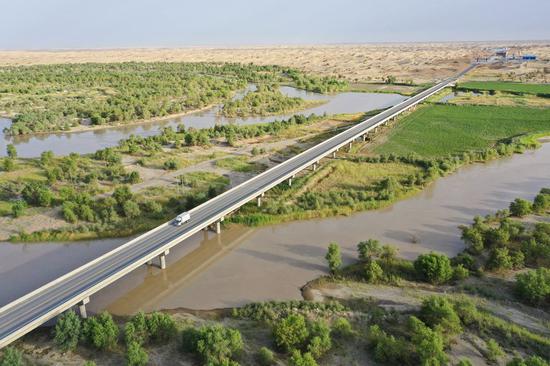 Aerial photo shows a section of a new desert highway traversing the Taklimakan Desert over the Tarim River in northwest China's Xinjiang Uygur Autonomous Region, June 22, 2022.  (Xinhua/Li Xiang)