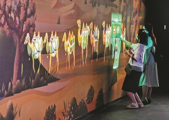 Visitors play an interactive game in May featuring the ancient Silk Road at an exhibition at the Xinjiang Uygur Autonomous Region Museum in Urumqi, the regional capital. (Photo/CHINA NEWS SERVICE)