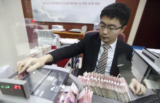 A teller counts cash at a bank in Taiyuan, Shanxi province. (Photo/China News Service)
