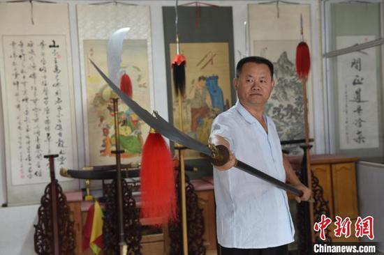 Wang Erbing and an arm he made. (Photo/China News Service)