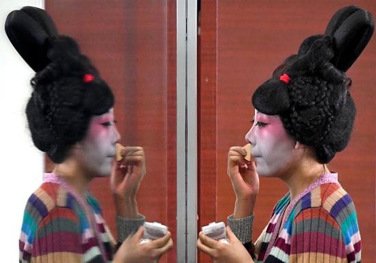 A dancer puts on makeup at Zhengzhou Song and Dance Theater in Zhengzhou, central China's Henan Province, Feb. 20, 2021. (Photo/Xinhua)