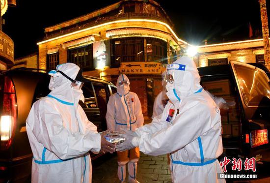 A volunteer hands over supplies to a medical worker, Lhasa, Tibet Autonomous Region, Aug. 14, 2022. (Photo/China News Service)