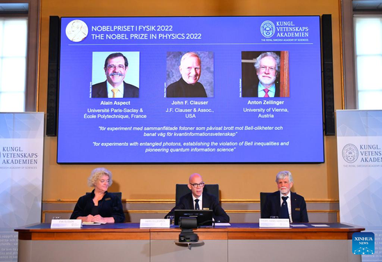 Portraits of the 2022 Nobel laureates in Physics Alain Aspect (L), John F. Clauser (C) and Anton Zeilinger are seen on a screen during the prize announcement in Stockholm, Sweden, Oct. 4, 2022.  (Xinhua/Ren Pengfei)